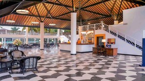 A spacious lobby with a checkered floor, a reception desk, and a staircase.