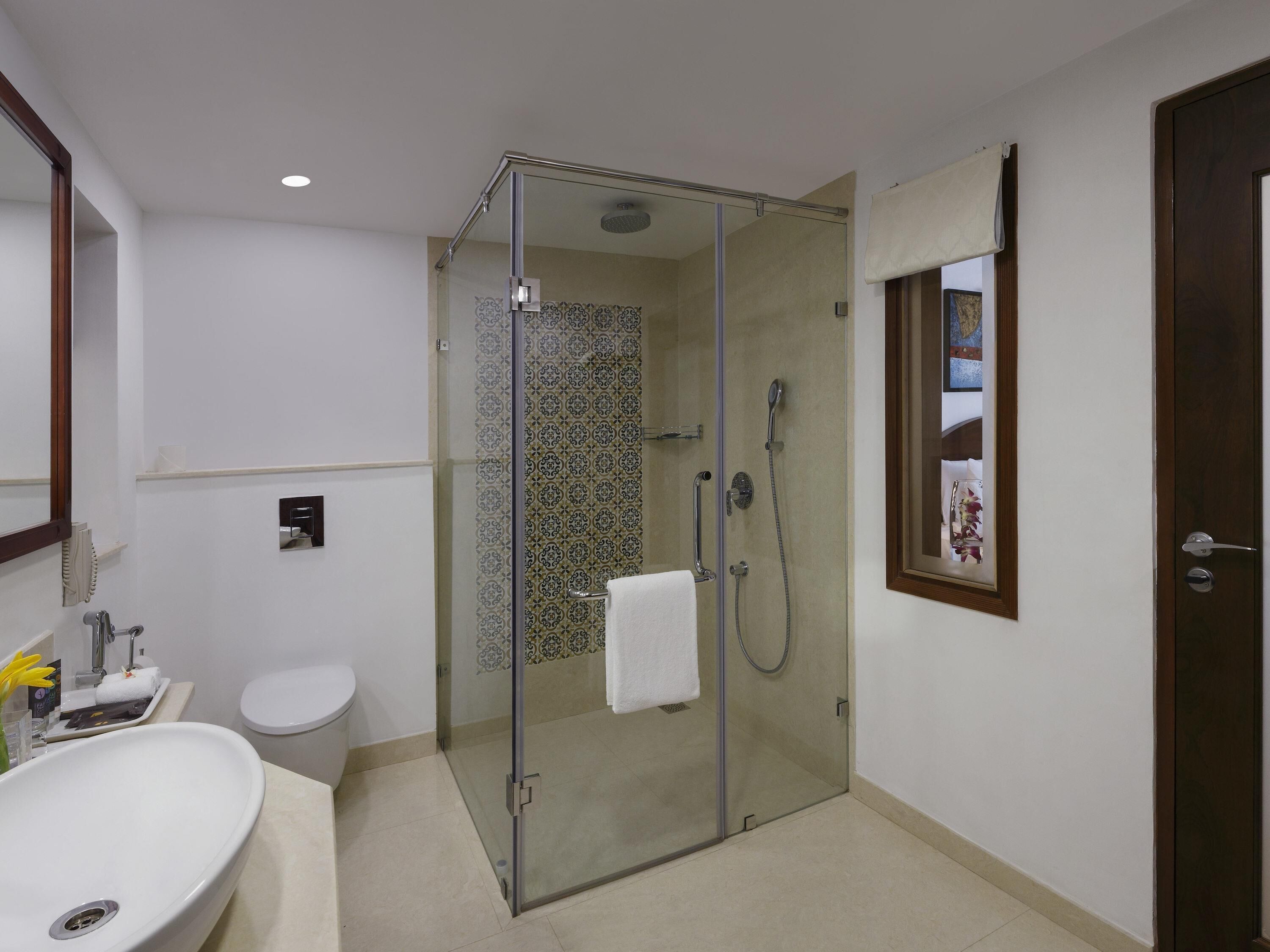 Un baño con ducha de vidrio, lavamanos blanco y un inodoro.
