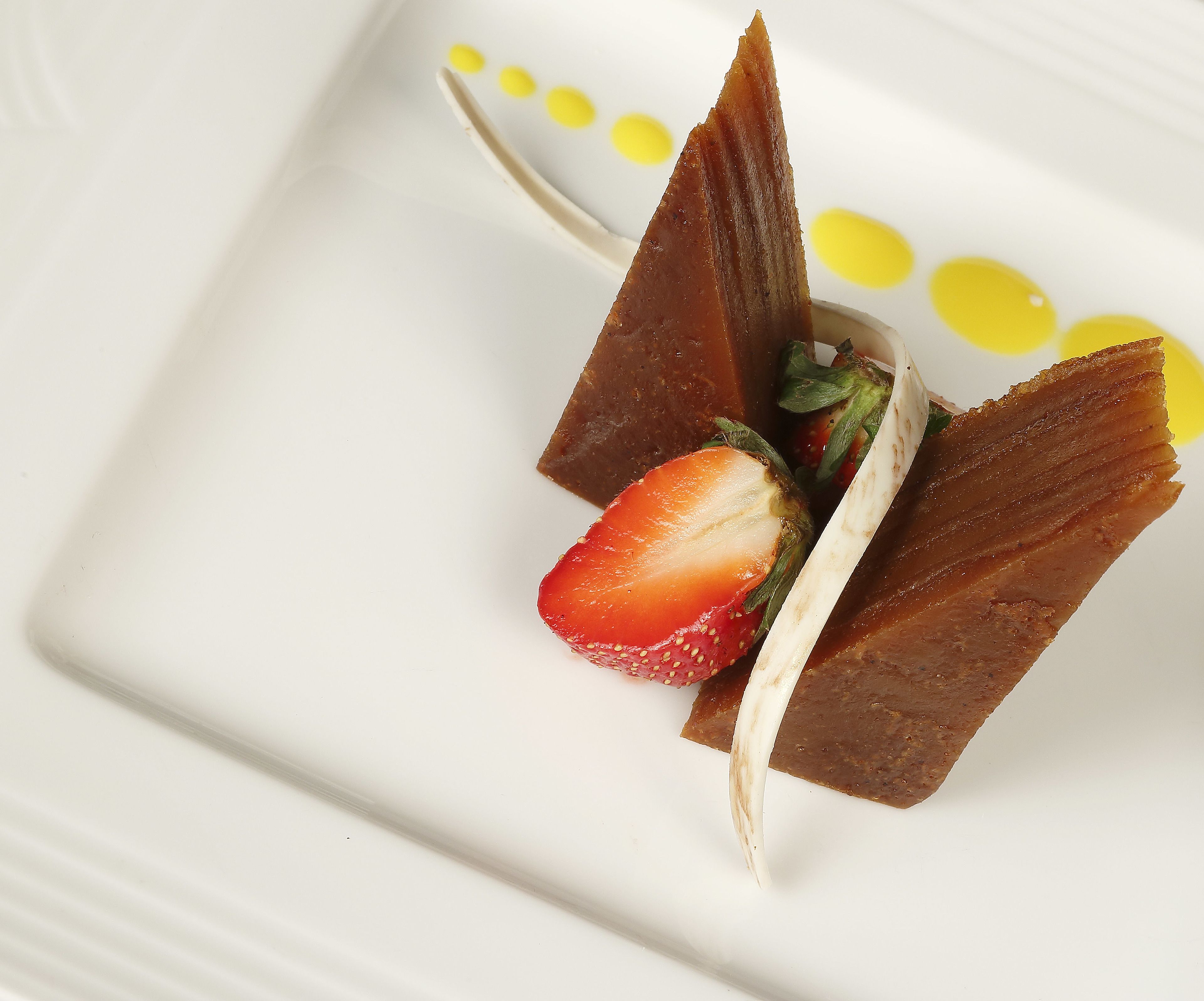 Dessert met aardbei en chocolade op een wit bord.