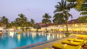 A swimming pool with lounge chairs and palm trees.