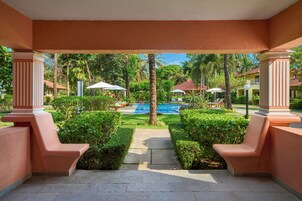 Un espacio al aire libre cubierto con piscina, palmeras y vista despejada de un edificio residencial al fondo.