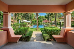 Un espace extérieur abrité doté d’une piscine, de palmiers et offrant une vue dégagée sur un immeuble d’habitation en arrière-plan.