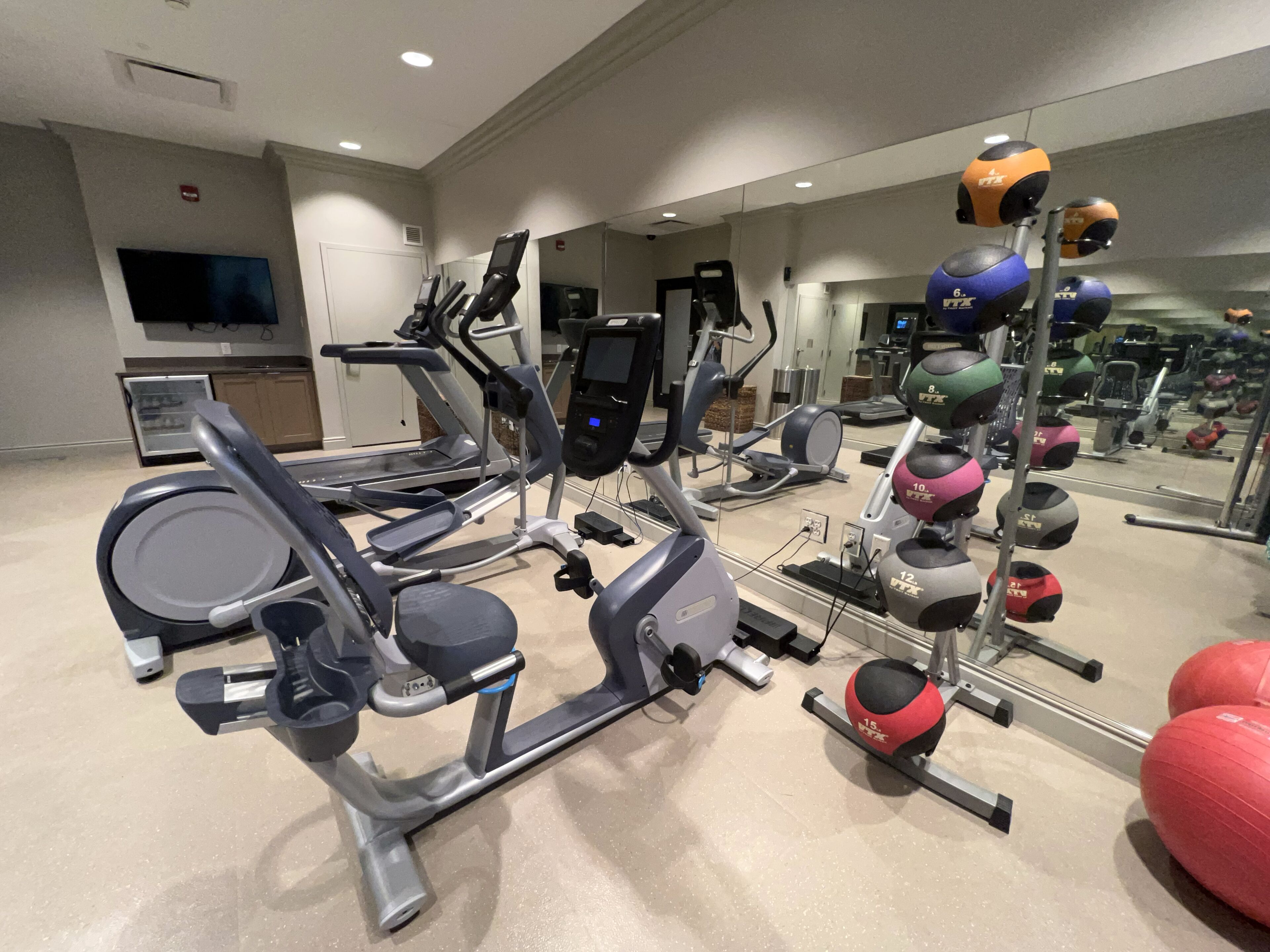 Een fitnessruimte met loopbanden, elliptische trainers en diverse gewichten.