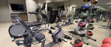 Een fitnessruimte met loopbanden, elliptische trainers en diverse gewichten.