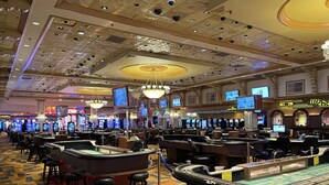 A casino with multiple gaming tables, slot machines, and a large chandelier.