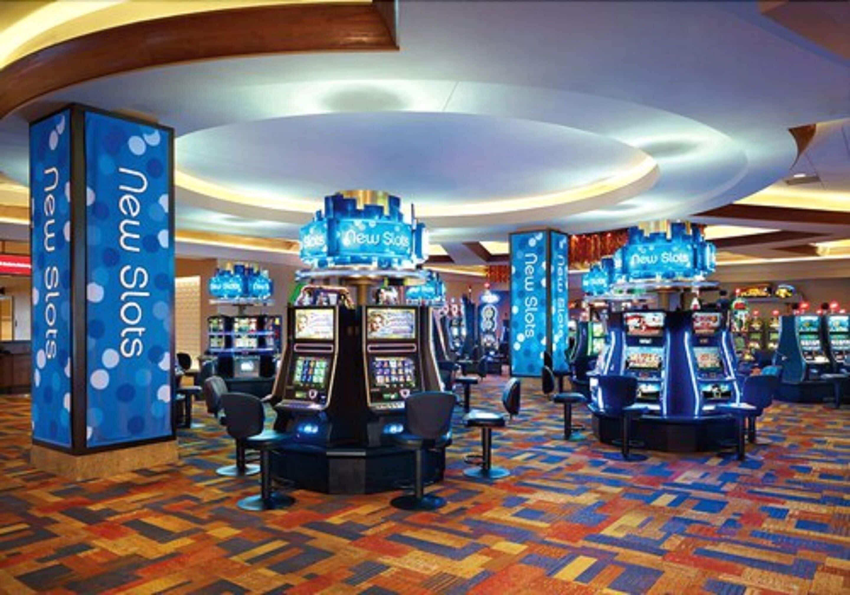 Une zone de casino comprenant de nombreux appareils à sous et un tapis à motifs.