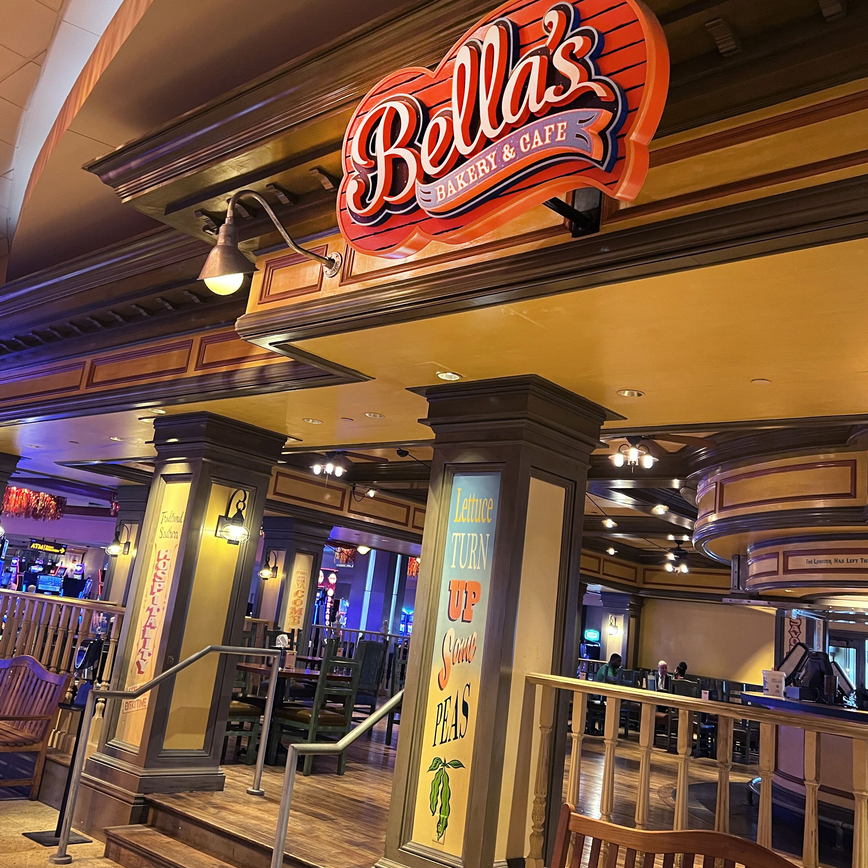 A restaurant interior with a prominent sign reading "Bella's Bakery & Cafe".