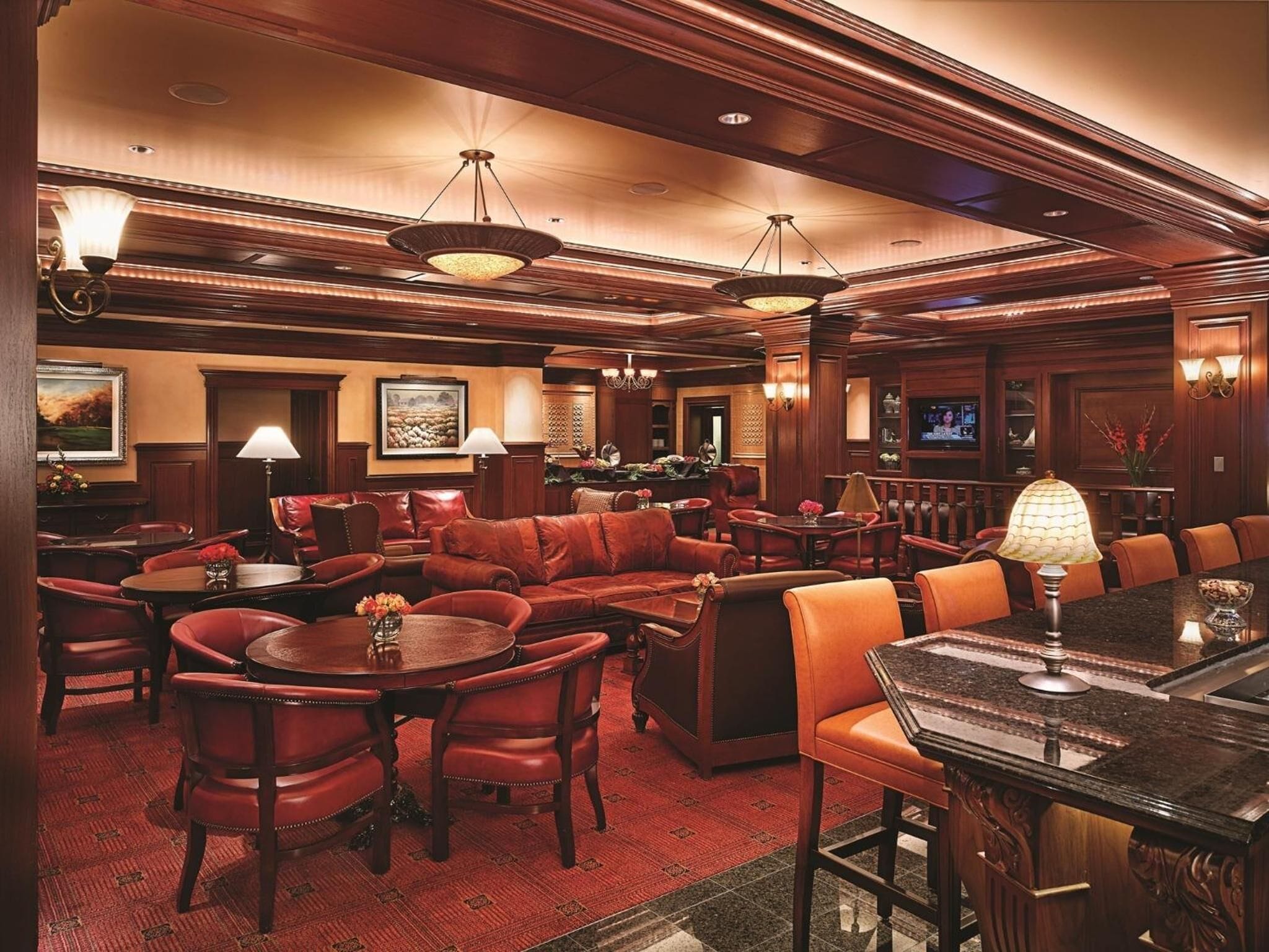 A spacious lobby with leather seating, a bar area, and a television screen.
