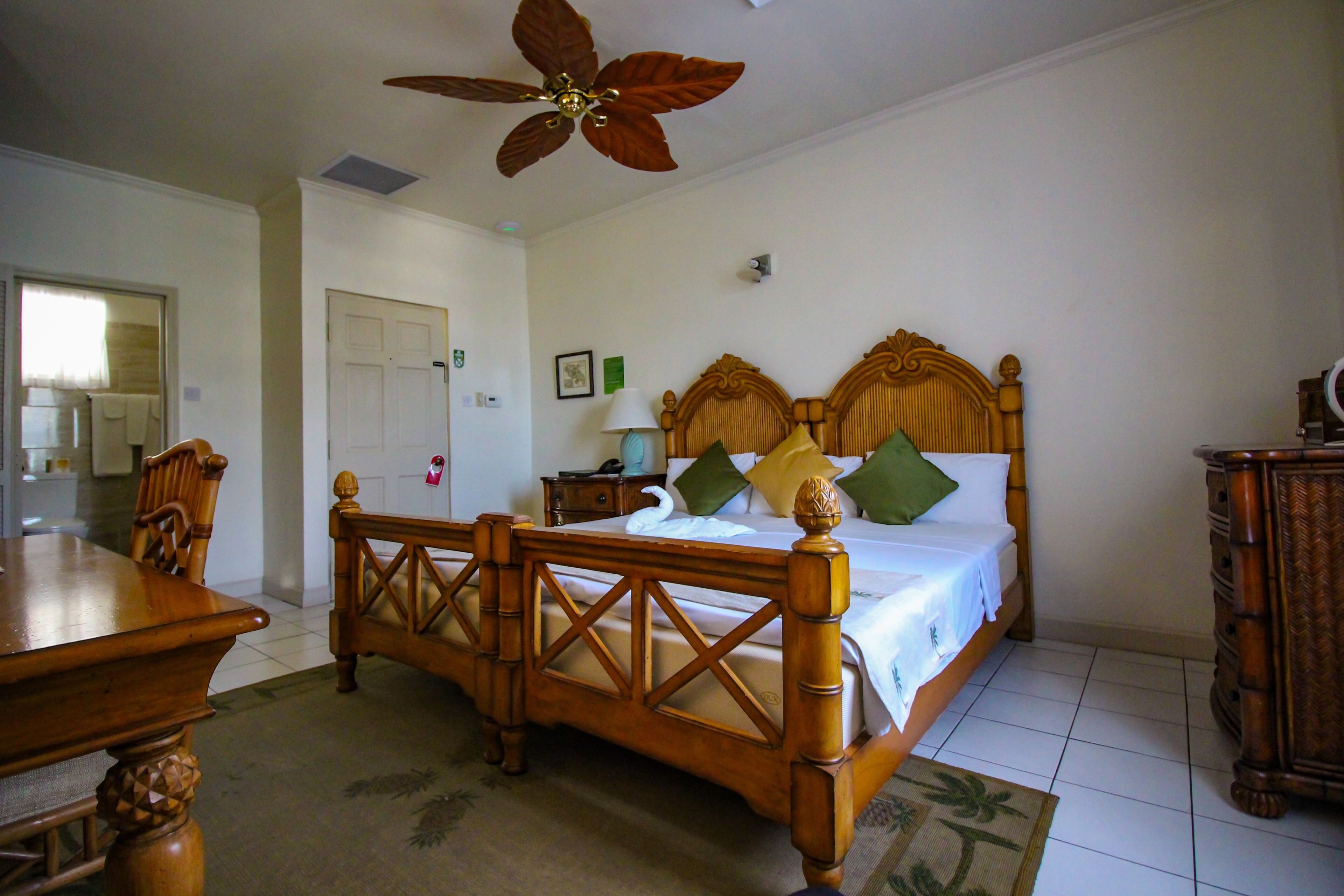 A bedroom with a wooden bed, a wooden desk, and a ceiling fan.