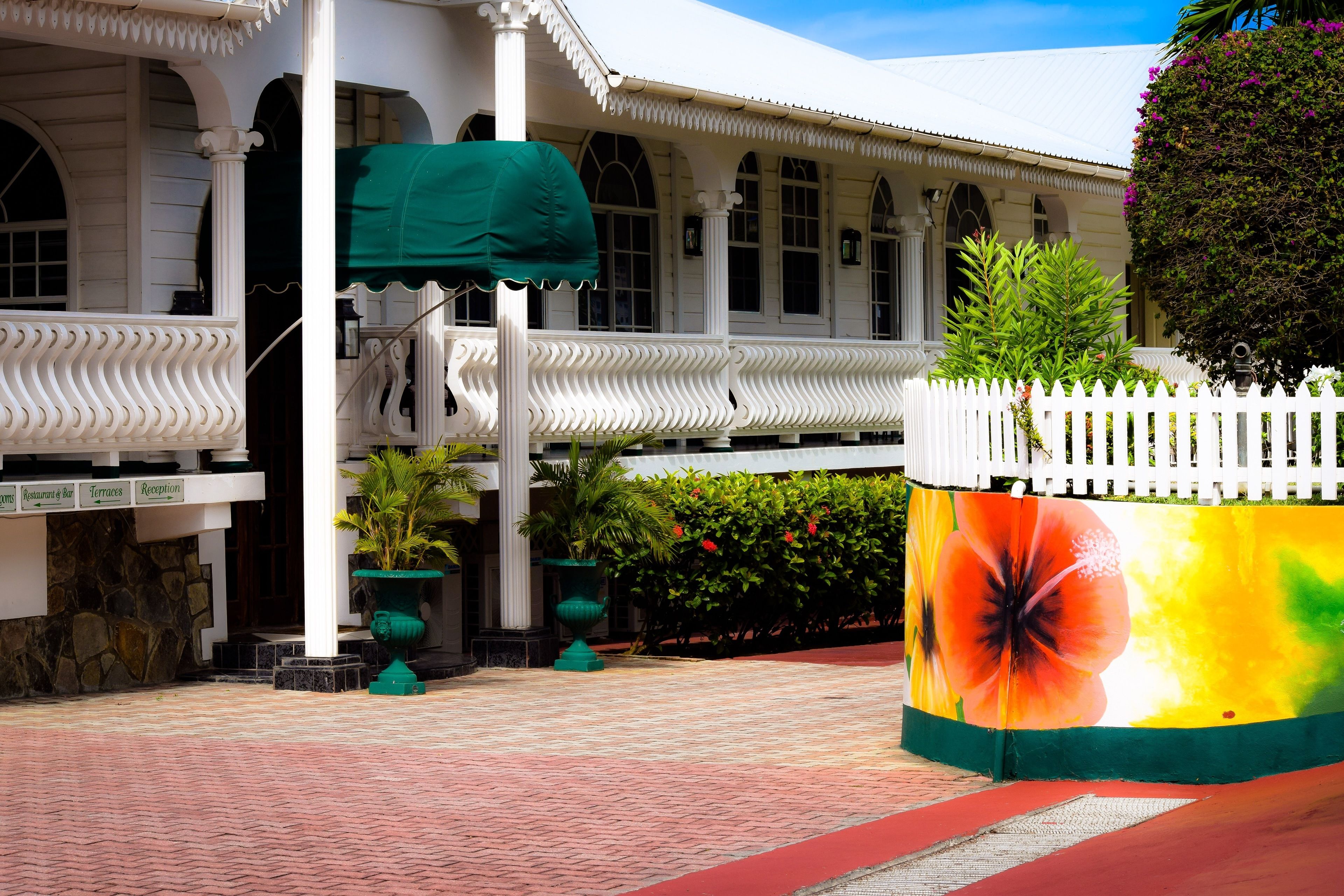 A white building with a covered porch, stone wall, and a sign indicating a restaurant and reception area.