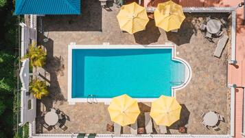 Vista aérea de uma área de piscina com espreguiçadeiras e guarda-sóis.