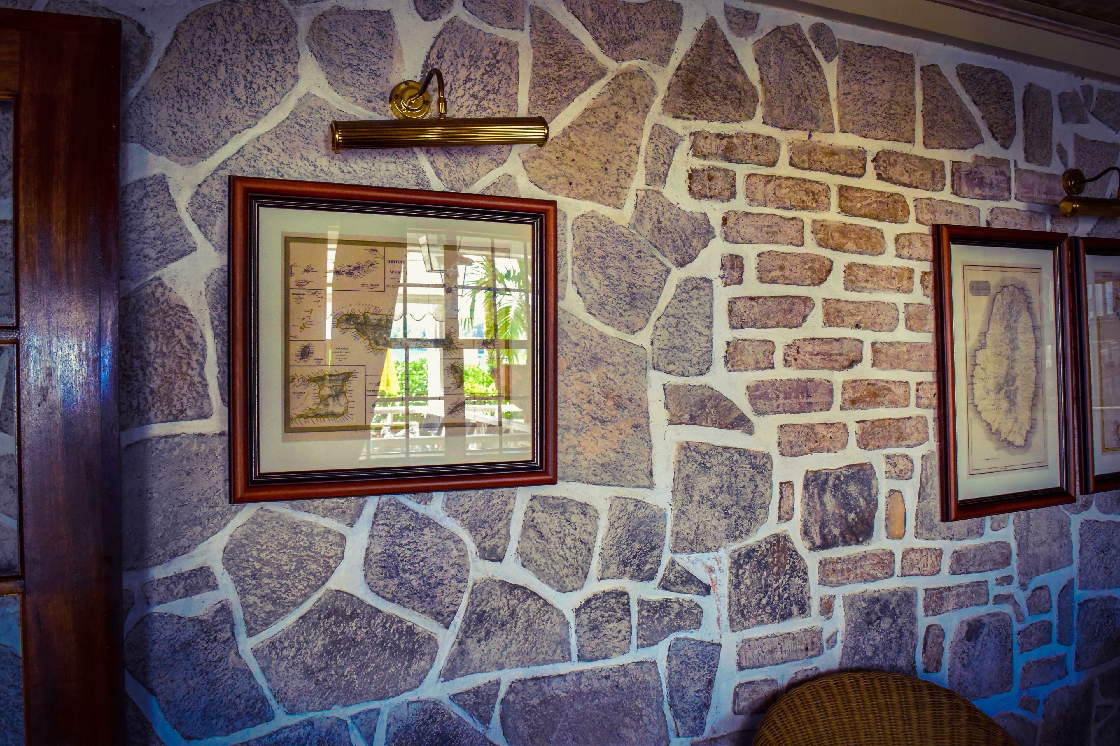 Un muro in pietra con quadri incorniciati e un lampadario dorato.