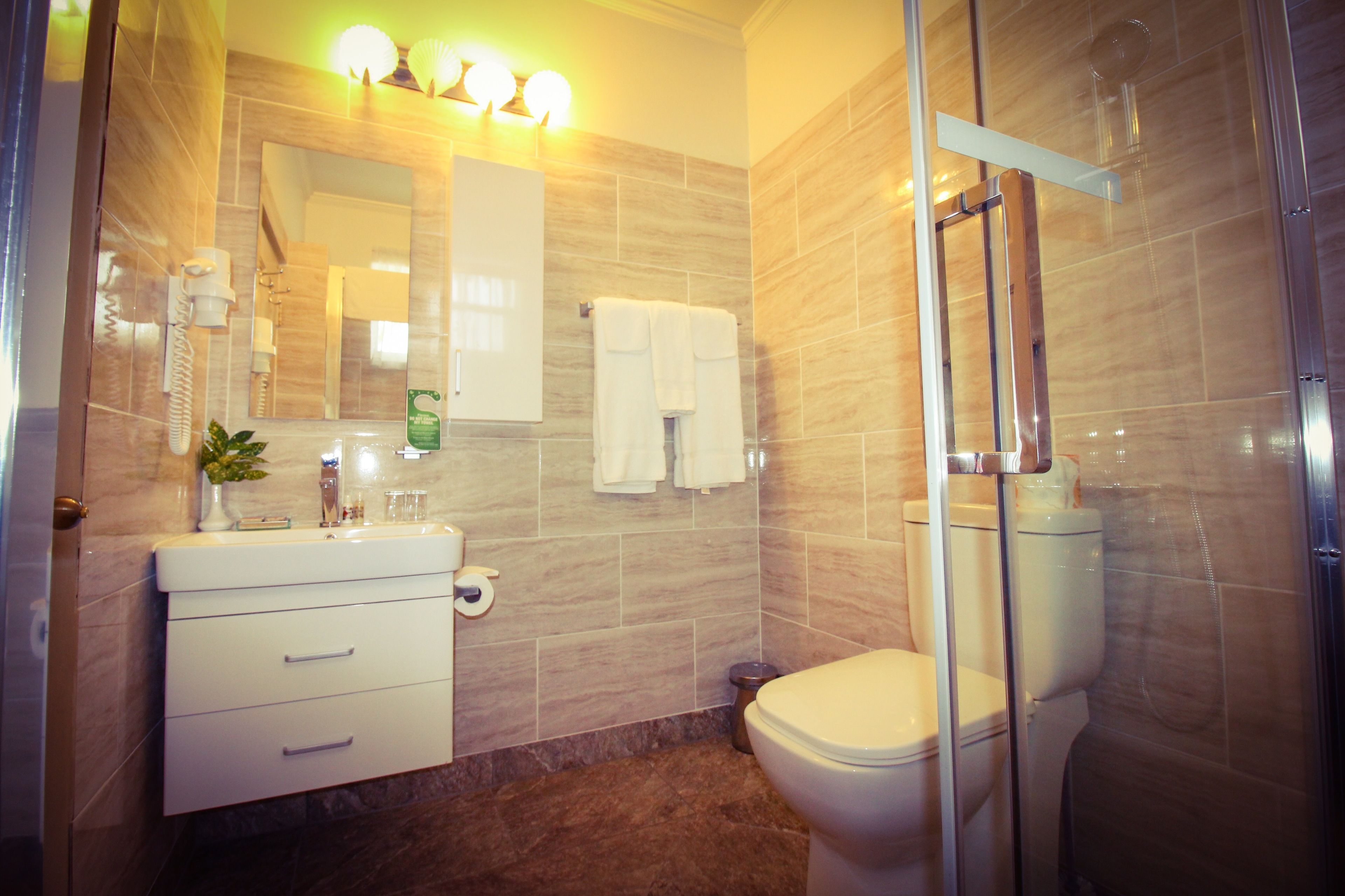 A modern bathroom with a glass shower enclosure, a white sink with a mirror above it, and a toilet with a glass shower door.