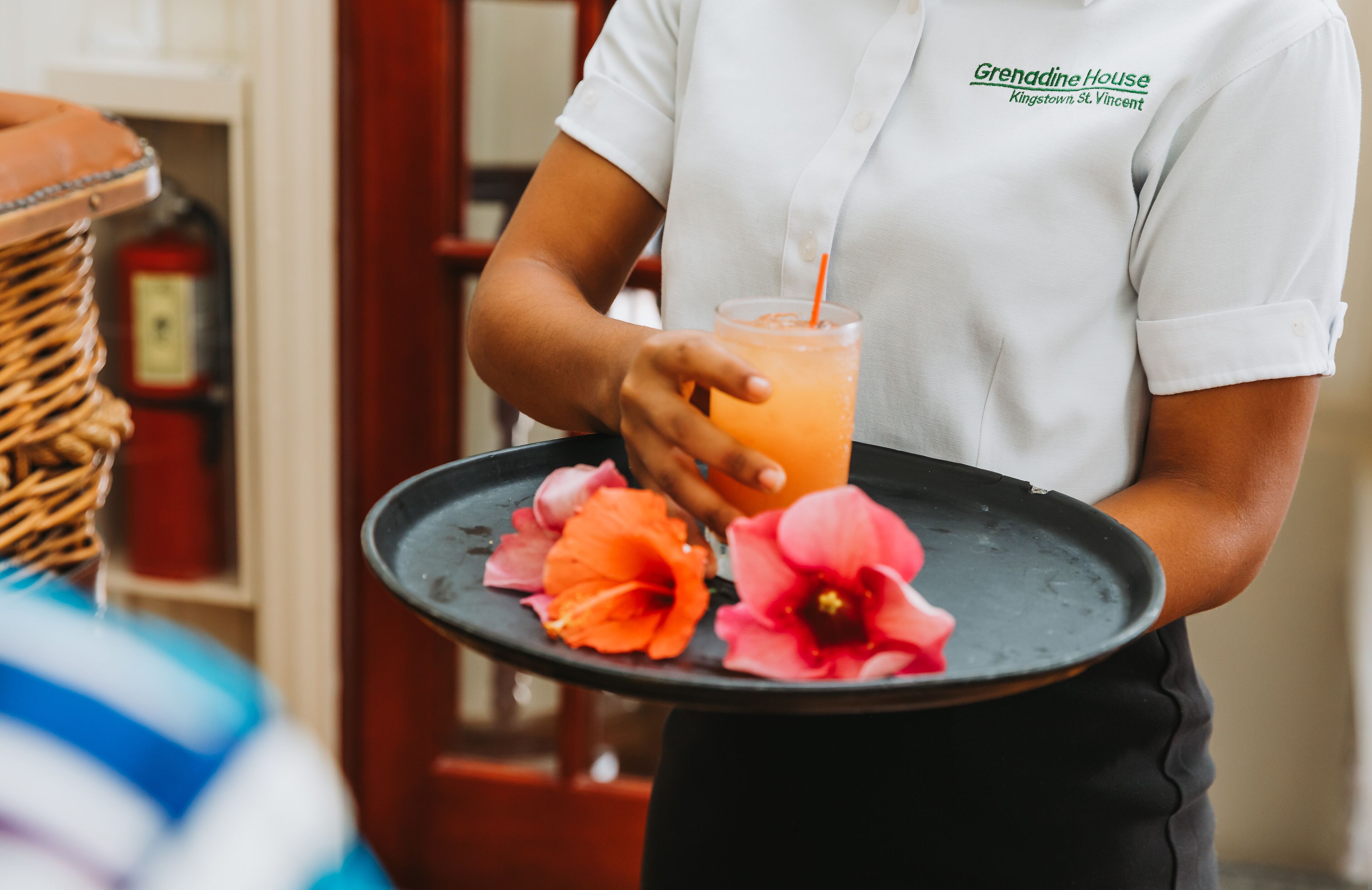 A person holding a tray with a drink and flowers.