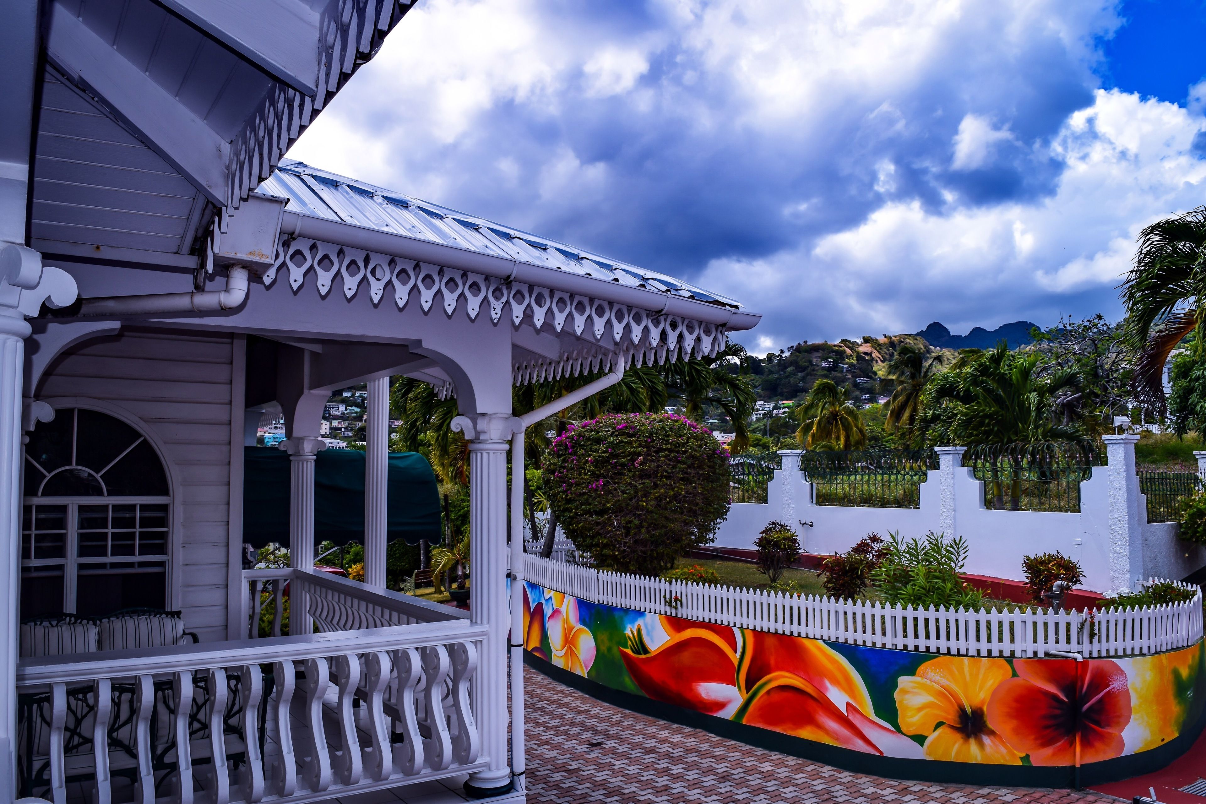 Un bâtiment blanc doté d’un porche et orné d’une fresque représentant des fleurs tropicales sur un de ses murs.