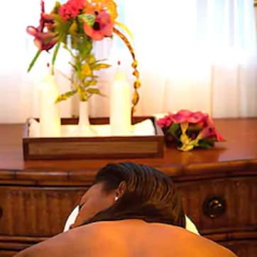 A room with a wooden dresser, a vase with flowers, and a candle holder.