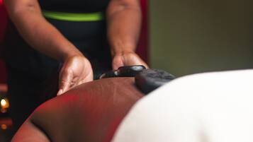 A massage therapy session in progress, with a therapist's hands applying pressure to a client's back.
