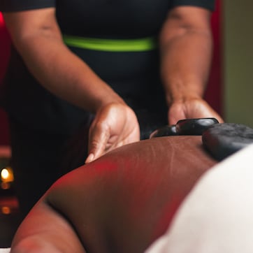 A massage therapy session in progress, with a therapist's hands applying pressure to a client's back.