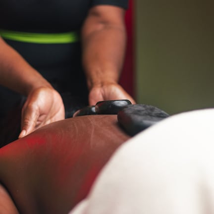 A massage therapy session in progress, with a therapist's hands applying pressure to a client's back.