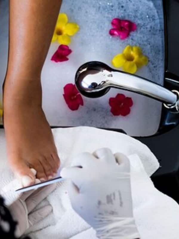 Relax in a bathtub filled with water and flower petals, complete with a modern faucet and a nearby towel.