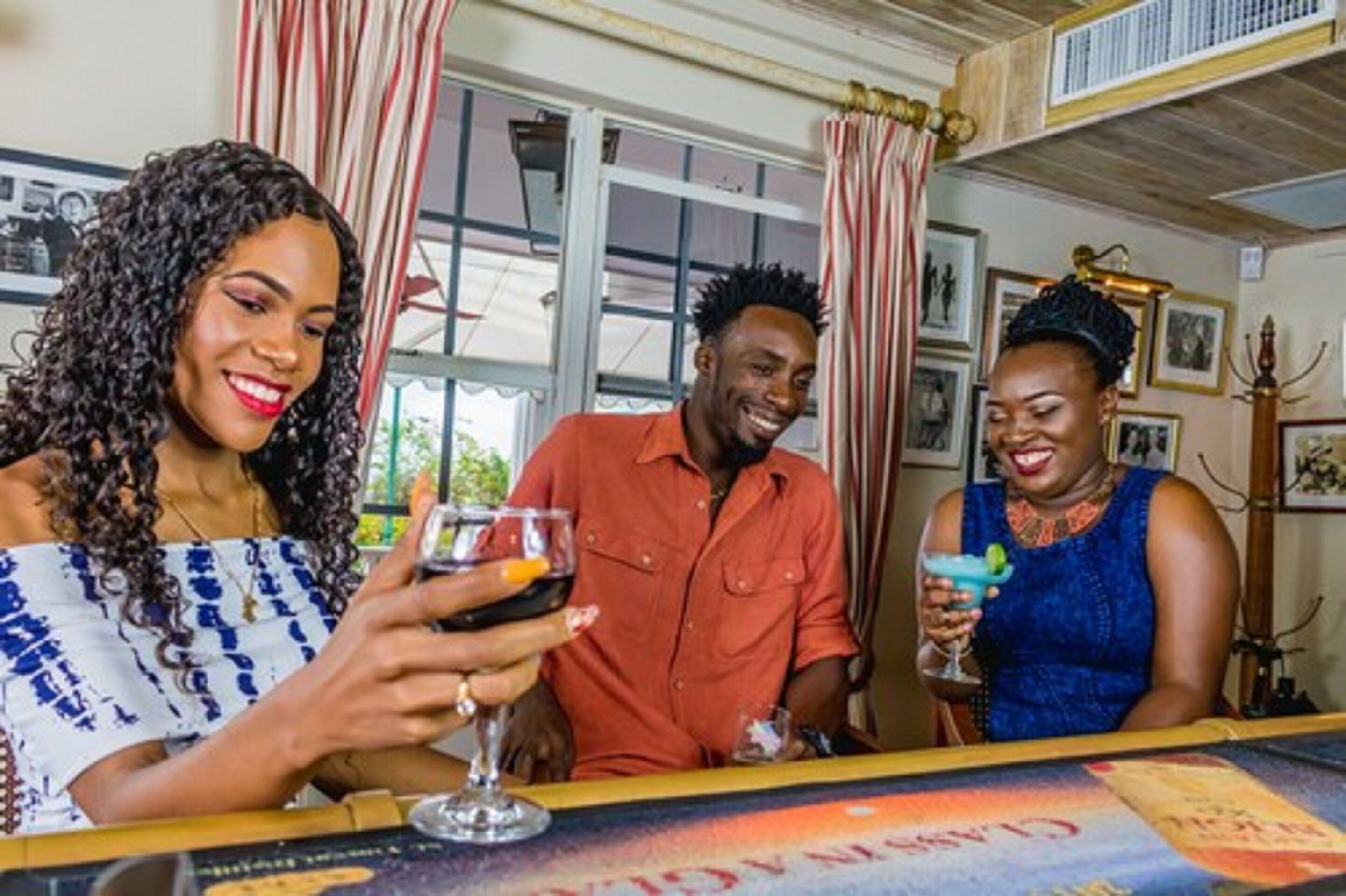 Trois personnes sont assises au bar, avec vue sur l’extérieur.