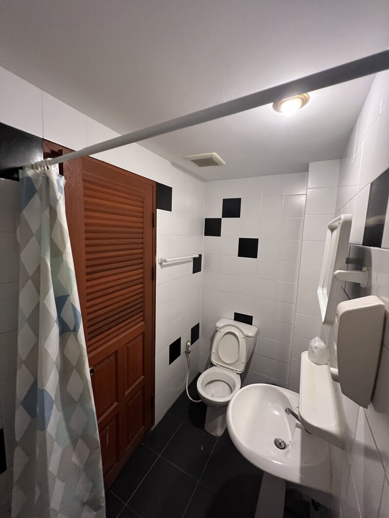 Un baño pequeño con inodoro, lavamanos y cortina de ducha.