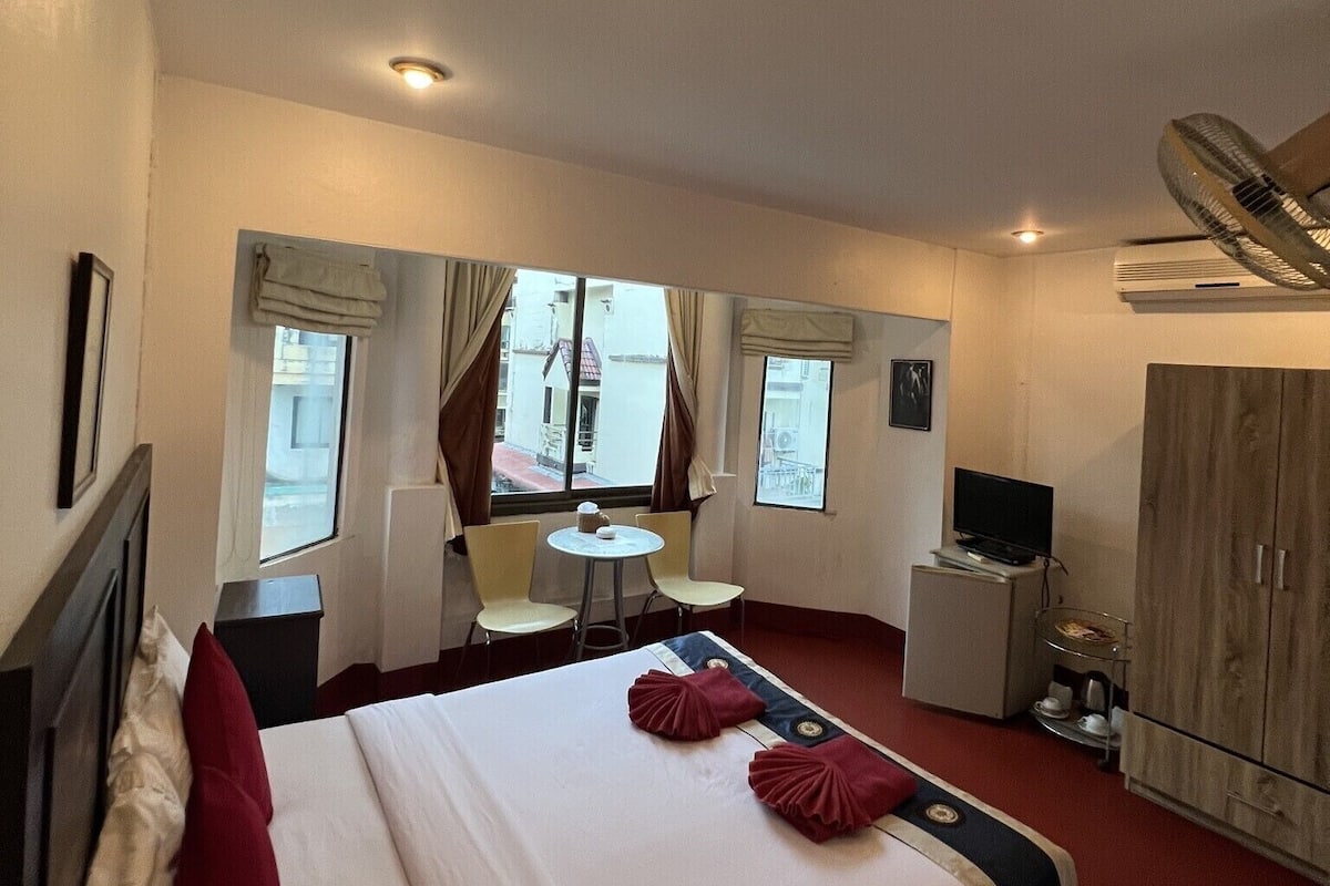 Hotellihuone, jossa on sänky, työpöytä, tuoli, televisio ja vaatekaappi.