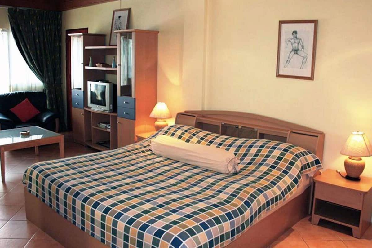 Hotellihuone, jossa on sänky, televisio, työpöytä ja tuoli.