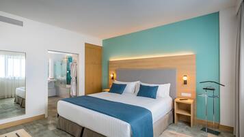 A hotel room with a large bed, a bedside table, a mirror, and a view of the bathroom.