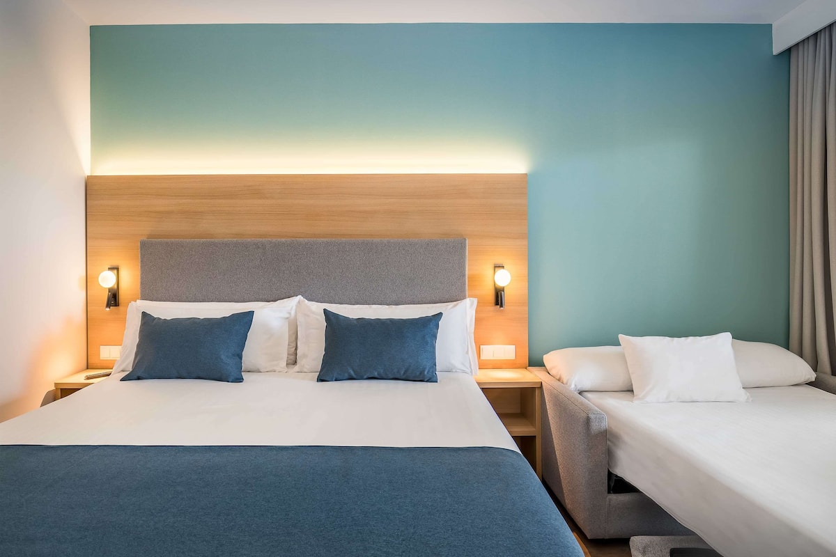 A hotel room with a large bed, two bedside tables, and a headboard.