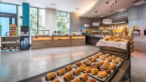 A modern kitchen with a variety of baked goods displayed on a counter and a refrigerator.