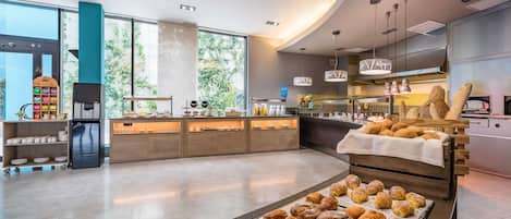 A modern kitchen with a variety of baked goods displayed on a counter and a refrigerator.
