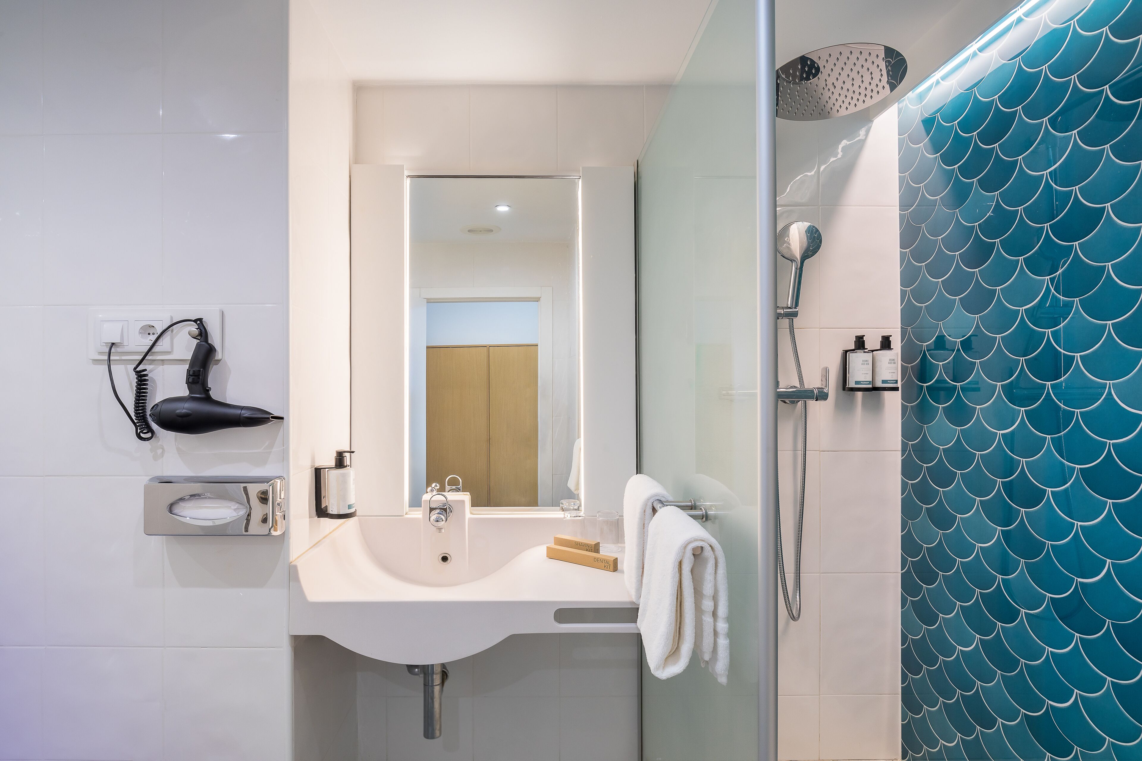 Un baño con lavabo, espejo y ducha.