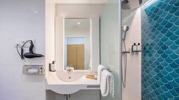 Un baño con lavabo, espejo y ducha.