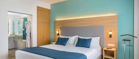 A hotel room with a bed, bedside tables, a wardrobe, and a bathroom visible through an open door.
