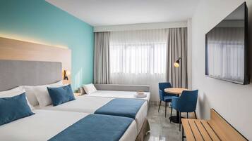 Habitación de hotel con dos camas, un sofá, un escritorio y una televisión.