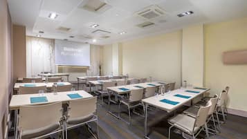 A conference room with multiple tables and chairs, equipped with water bottles and notepads.