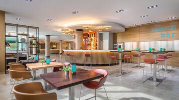 A modern snack bar with a curved counter, seating area with tables and chairs, and a wooden accent wall.