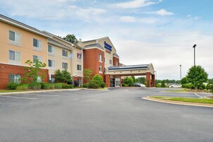 A hotel with a brick facade, a covered entrance, and a parking lot.