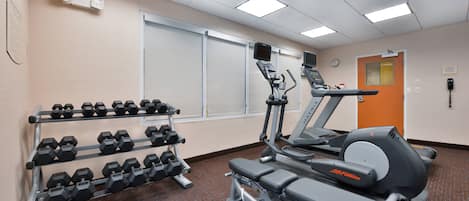 A gym with treadmills, ellipticals, and dumbbells.