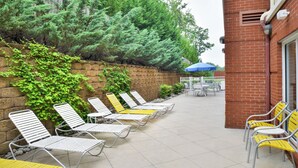 A patio area with sun loungers and a brick wall. - Fairfield Inn & Suites by Marriott Asheboro (Asheboro)