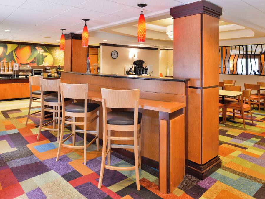 Un hall de hotel con una zona de bar central, varias opciones de asientos y una alfombra colorida.