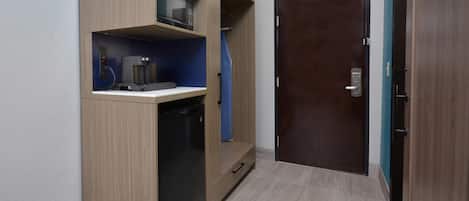 A compact room with a built-in microwave, coffee maker, and a small dishwasher.