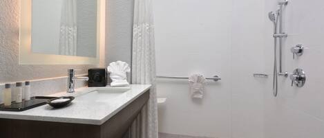 A modern bathroom with a large mirror, a vanity with a sink, a shower area, and a towel rack.