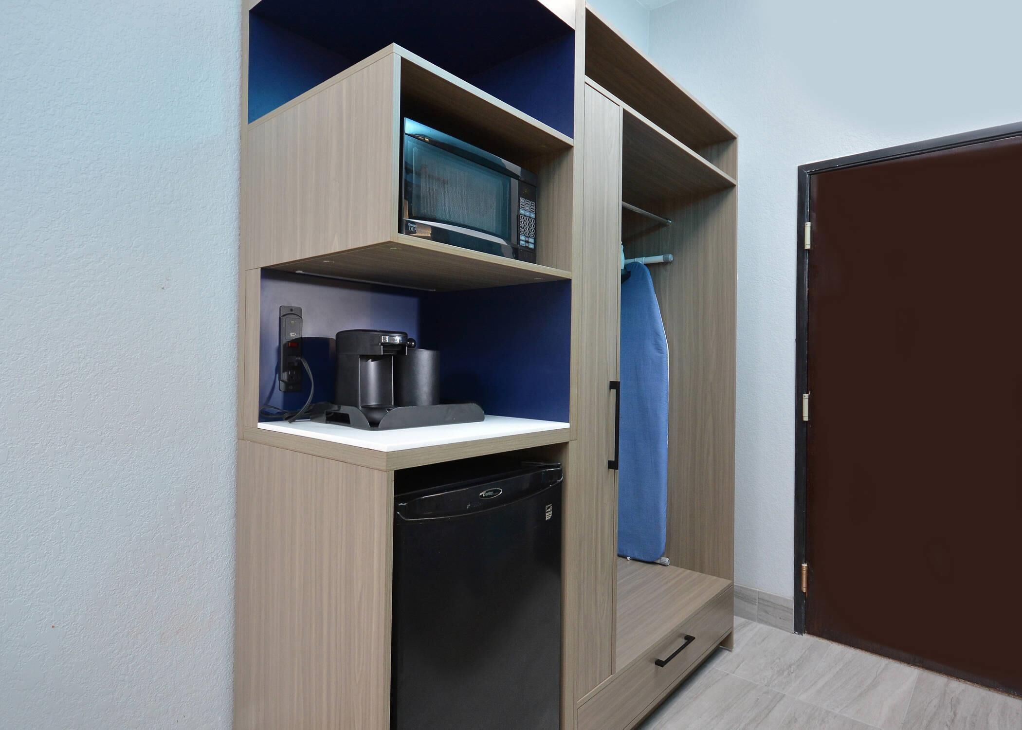 A compact kitchenette with a microwave, coffee maker, and dishwasher.