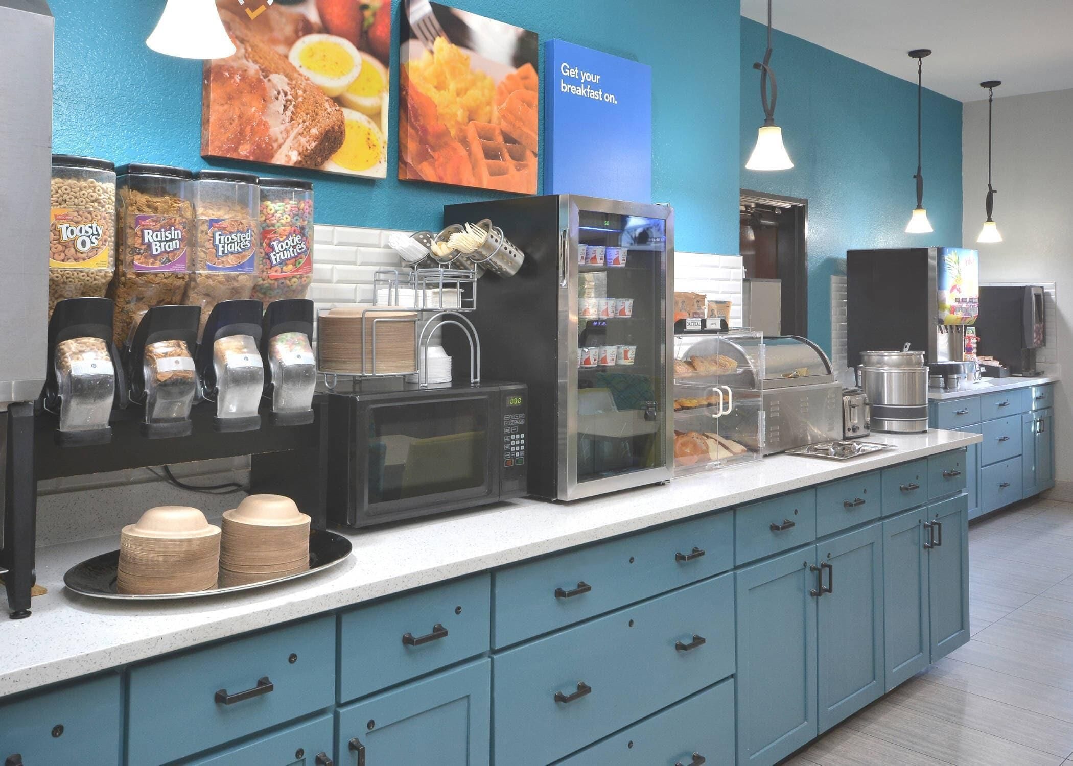 A breakfast bar with cereal dispensers, a microwave, and a refrigerator.