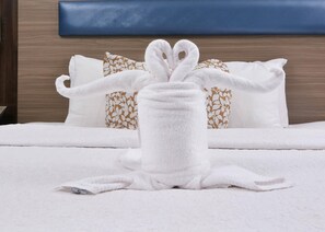 A neatly made bed with white bedding and a towel arranged in a bunny shape. - Brookstone Lodge near Biltmore Village, an Ascend Collection Hotel (Asheville)