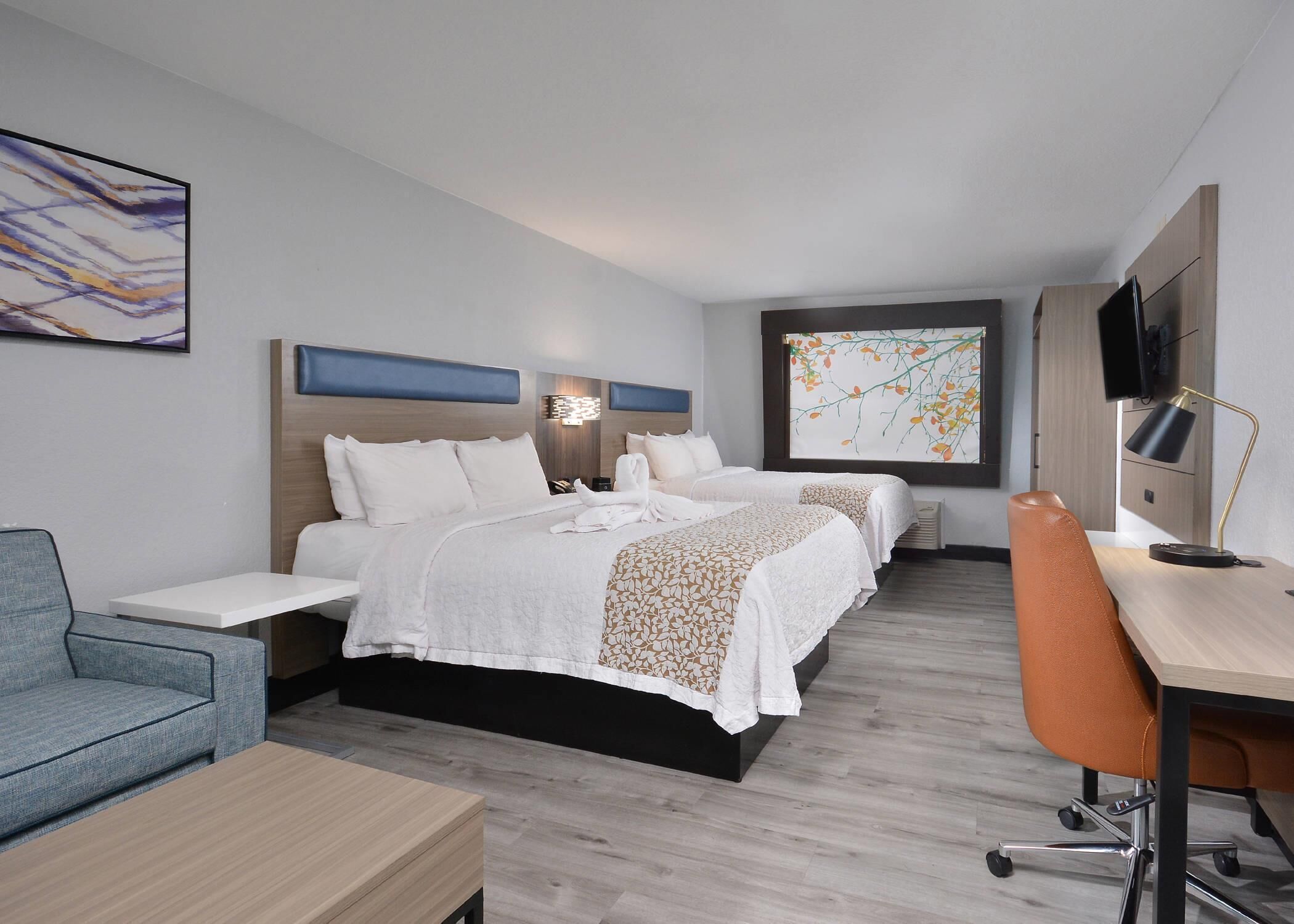 Una habitación de hotel moderna con una cama, un escritorio, una silla y un televisor.