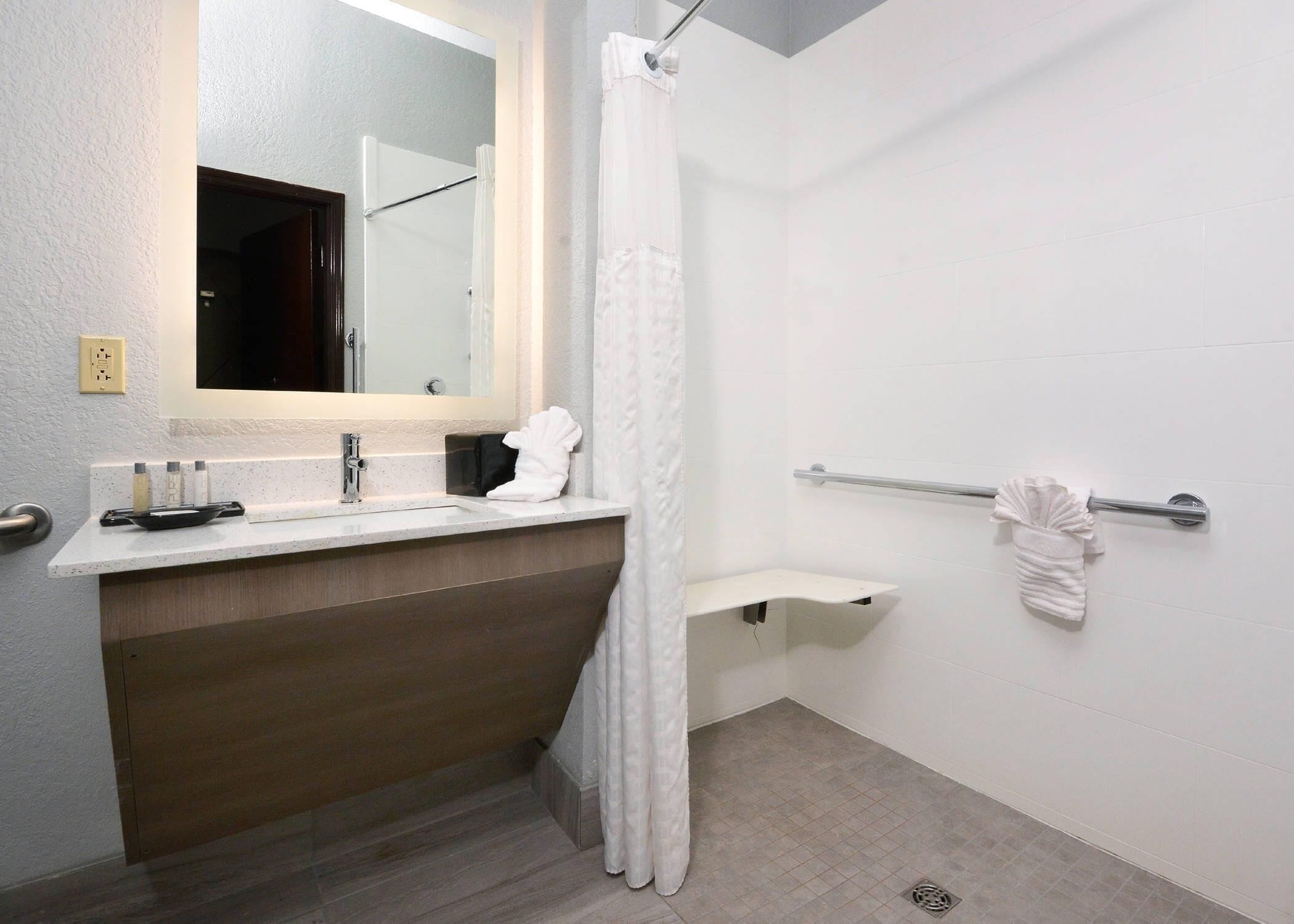 Un baño moderno con ducha, lavabo, espejo y toallero.