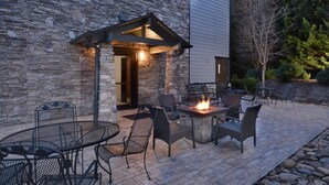 An outdoor patio with stone walls, a fire pit, and metal furniture.